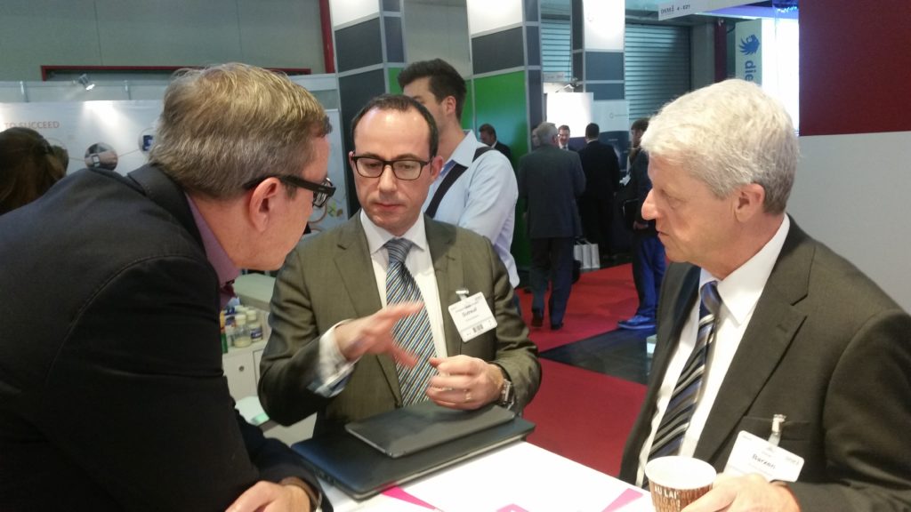 Elmar Barzen und der französische Chefentwickler von Prima Solutions im Gespräch mit Holger Koppius am Stand der Asspario AG
